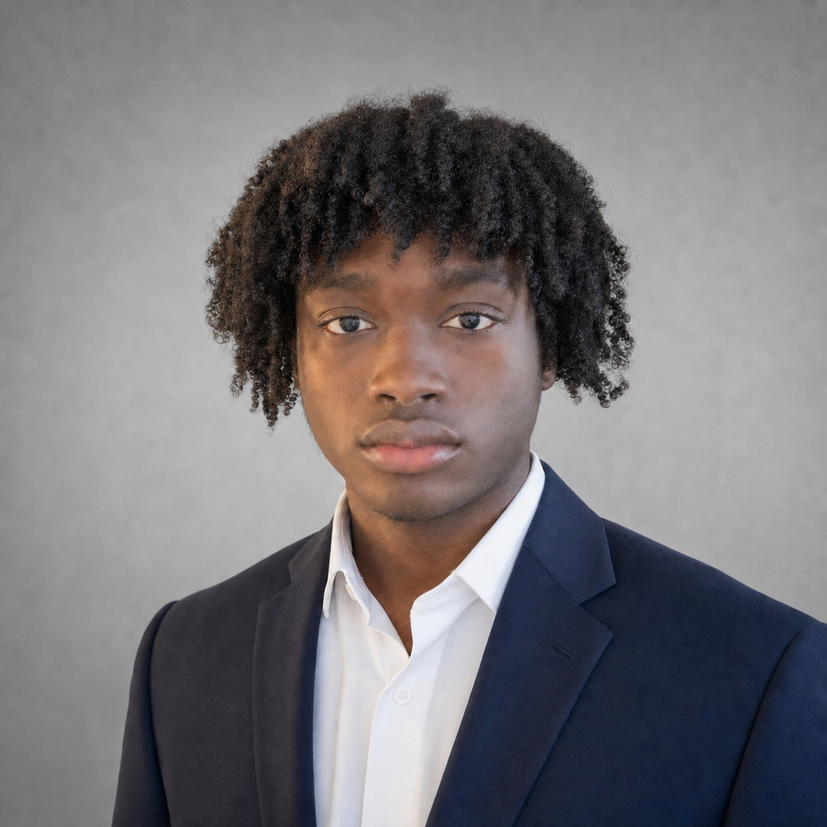 Christian Valentin, photographed in a navy suit against a grey studio wall